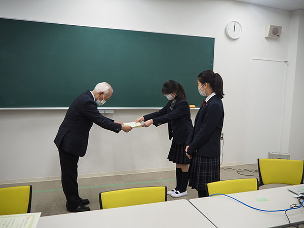 東京家政_大賞に選ばれ、校長から賞状を授与されるチームの代表者